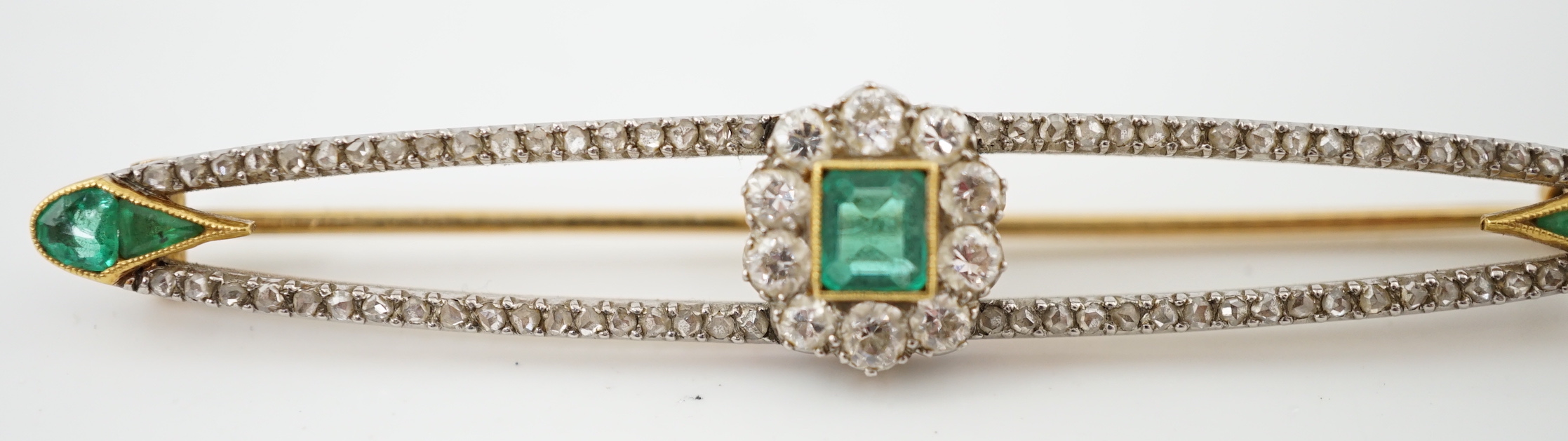 A Belle Epoque gold and platinum, emerald and round cut diamond cluster set elliptical bar brooch